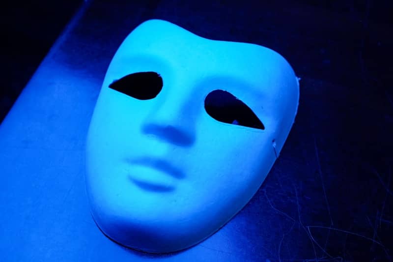 A white mask with black eyes on a blue background