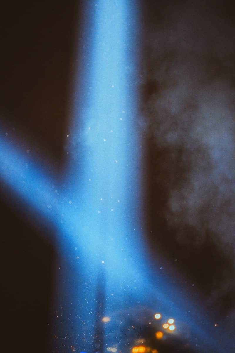 A bright blue spotlight shines through smoke.