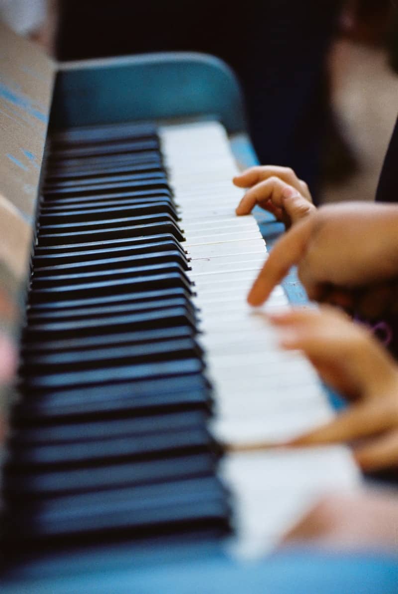Child's hands on worn keys of blue piano