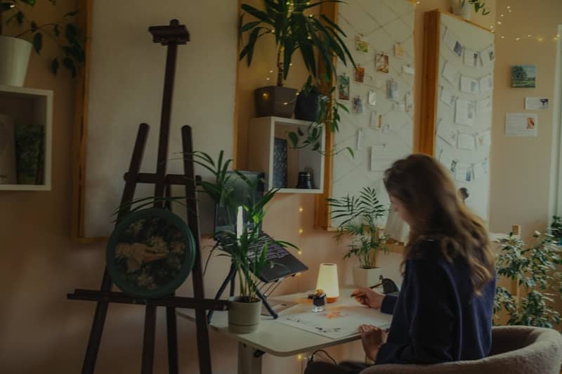 Young woman drawing at a desk in a cozy room.