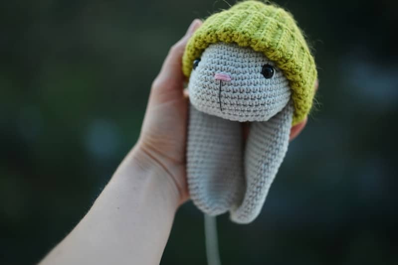 Hand holding a crocheted bunny wearing a hat