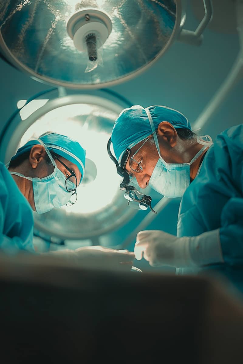 Two surgeons performing a delicate operation under bright lights.