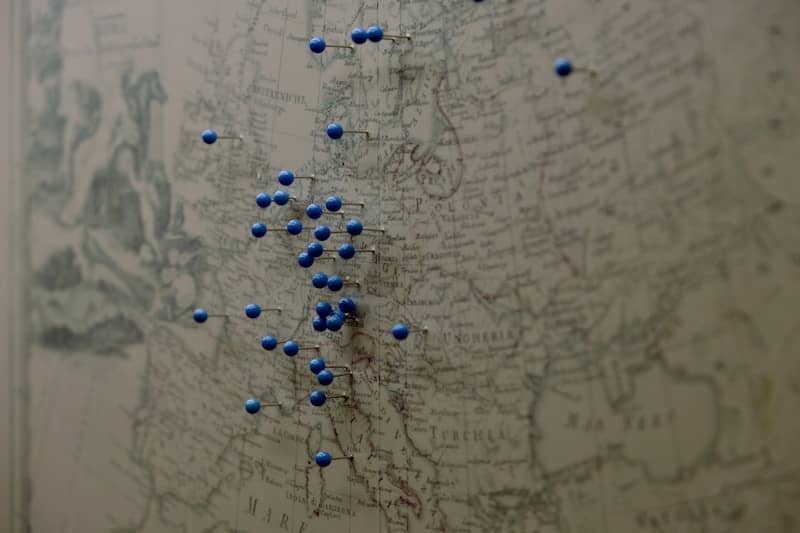 Blue push pins marking locations on an antique map of Europe
