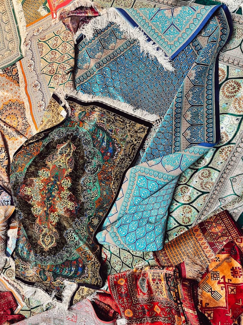 A pile of colorful, intricately patterned rugs.
