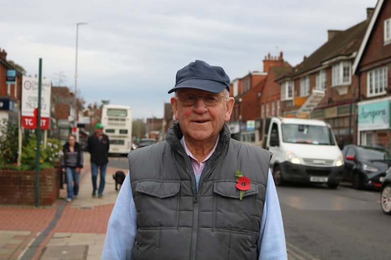An elderly man wearing a poppy on his vest.