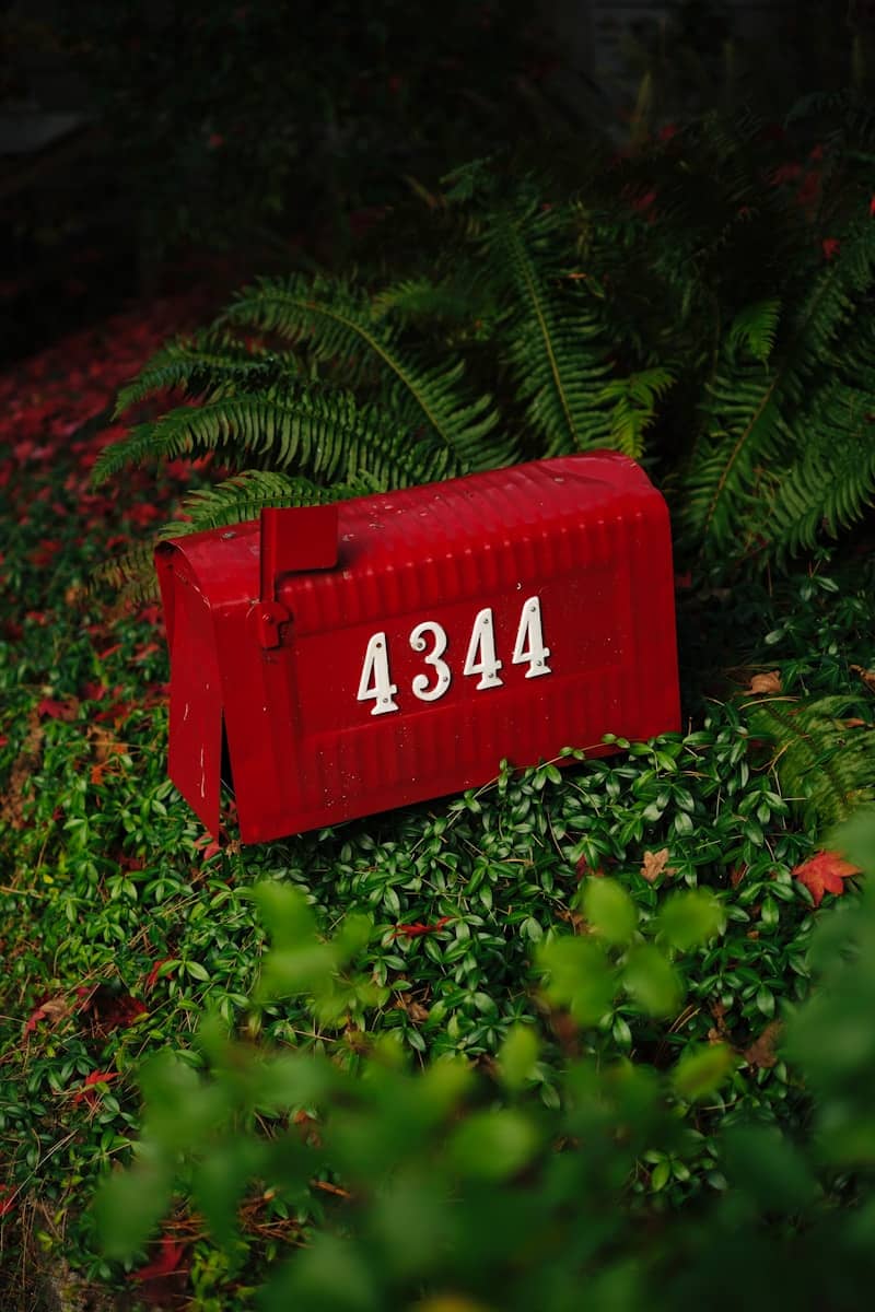 Red mailbox with house number 4344 among greenery