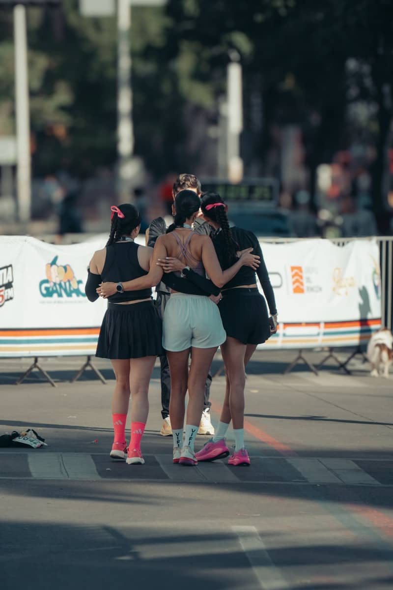 Four friends embrace after a race, celebrating together.