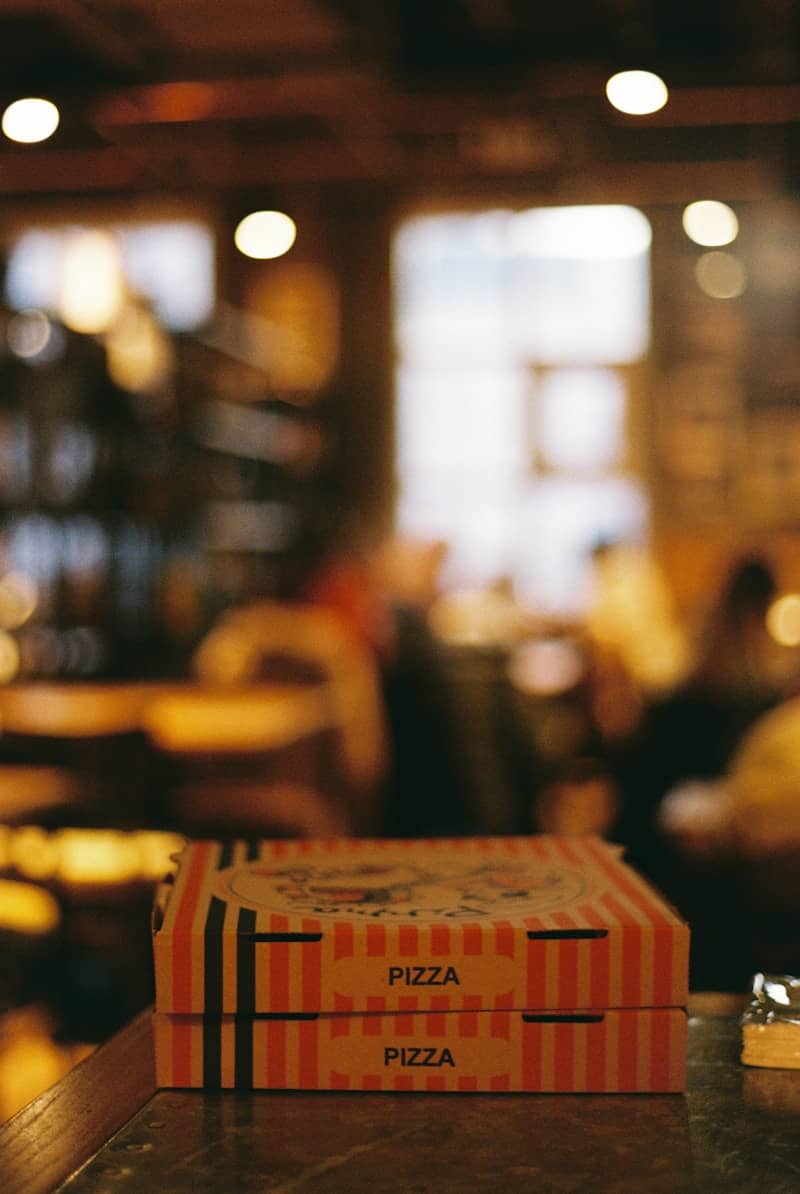 Two pizza boxes stacked on a counter