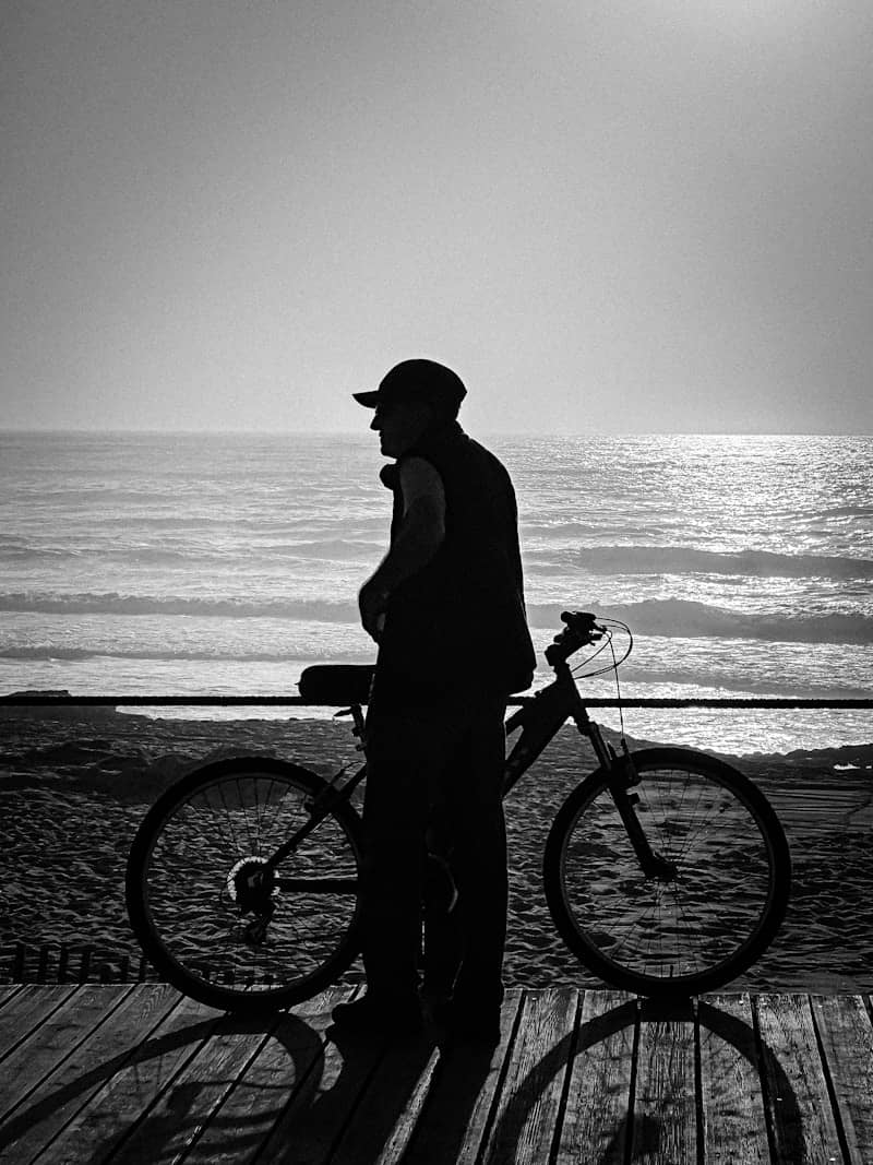 Man with bicycle on boardwalk by the ocean