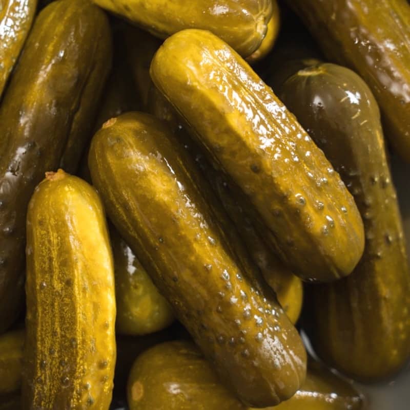 A pile of whole green dill pickles.