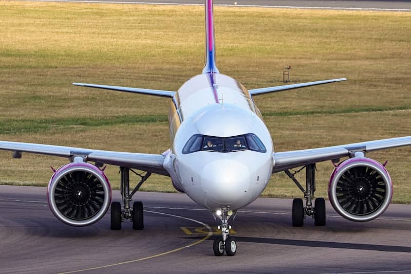 A white passenger airplane with purple accents on a runway.