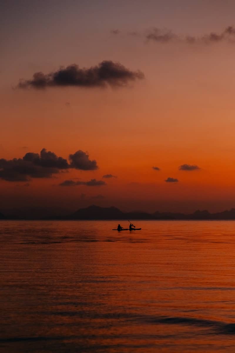 Two people paddleboarding at sunset