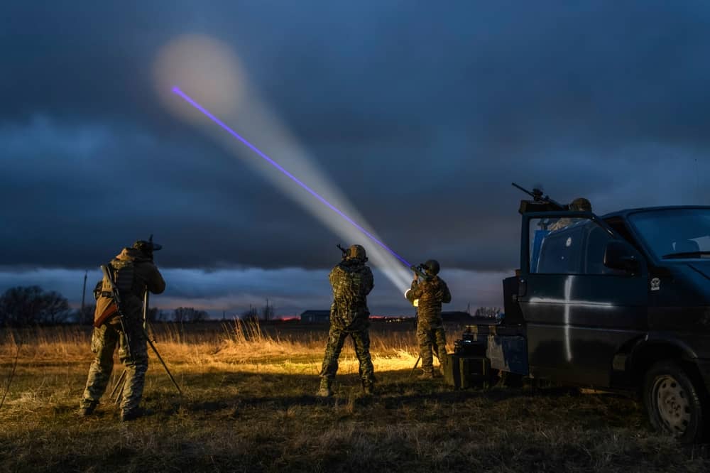 An air defense unit of the Ukrainian Armed Forces scans the sky with a spotlight while operating a truck-mounted heavy machine gun during a nighttime operation. (paparazzza/Shutterstock.com)