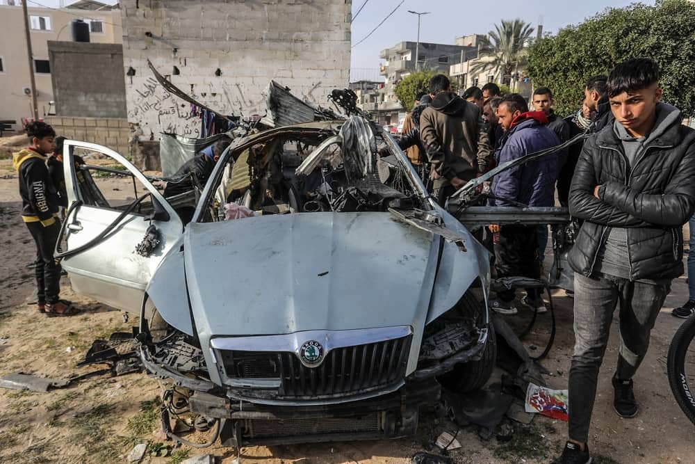 Palestinians inspect a wrecked car, as a result of Israeli occupation aircraft targeting a civilian car, in the city of Rafah in the southern Gaza Strip.