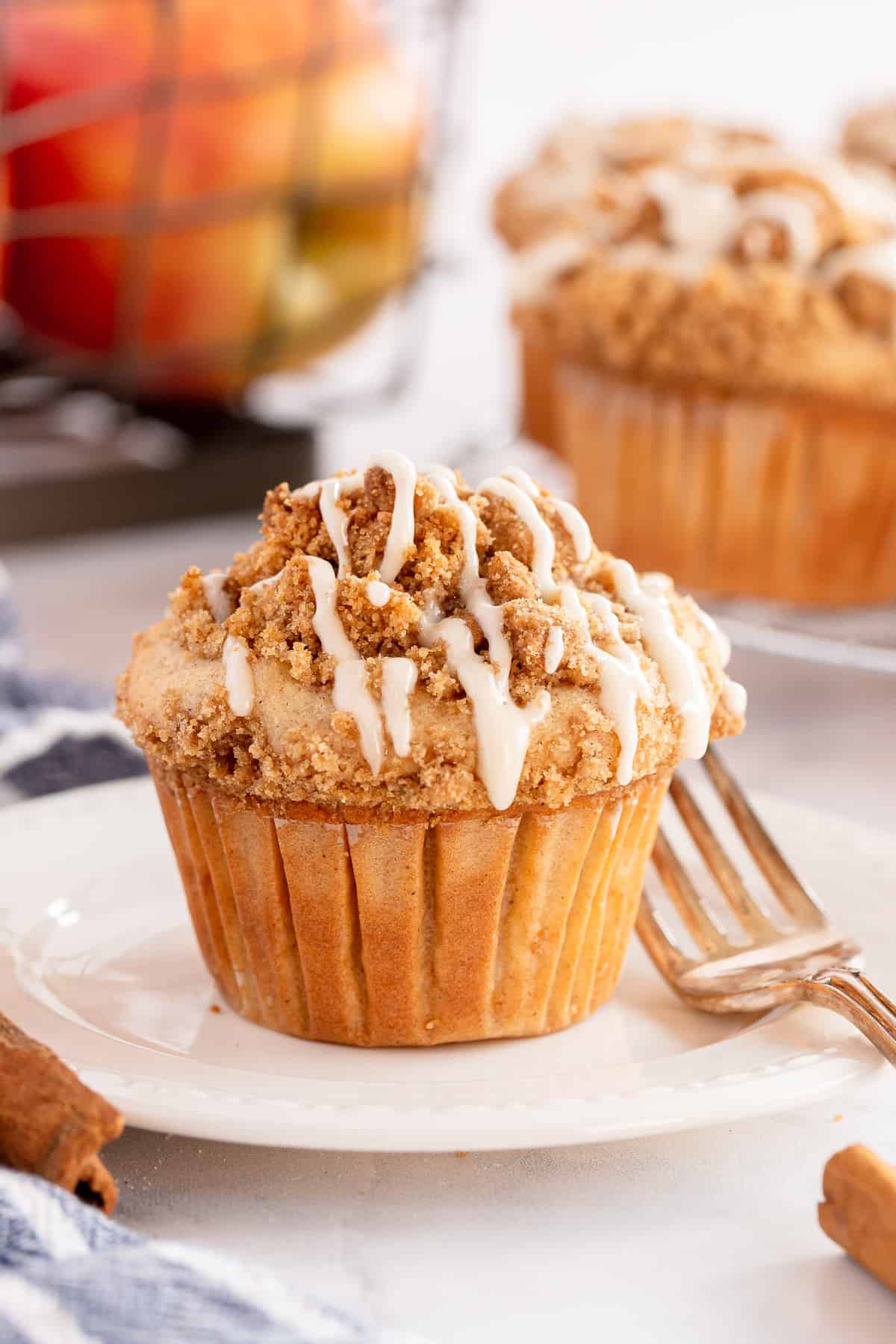 A glazed apple coffee cake muffin on a plate with aa fork.