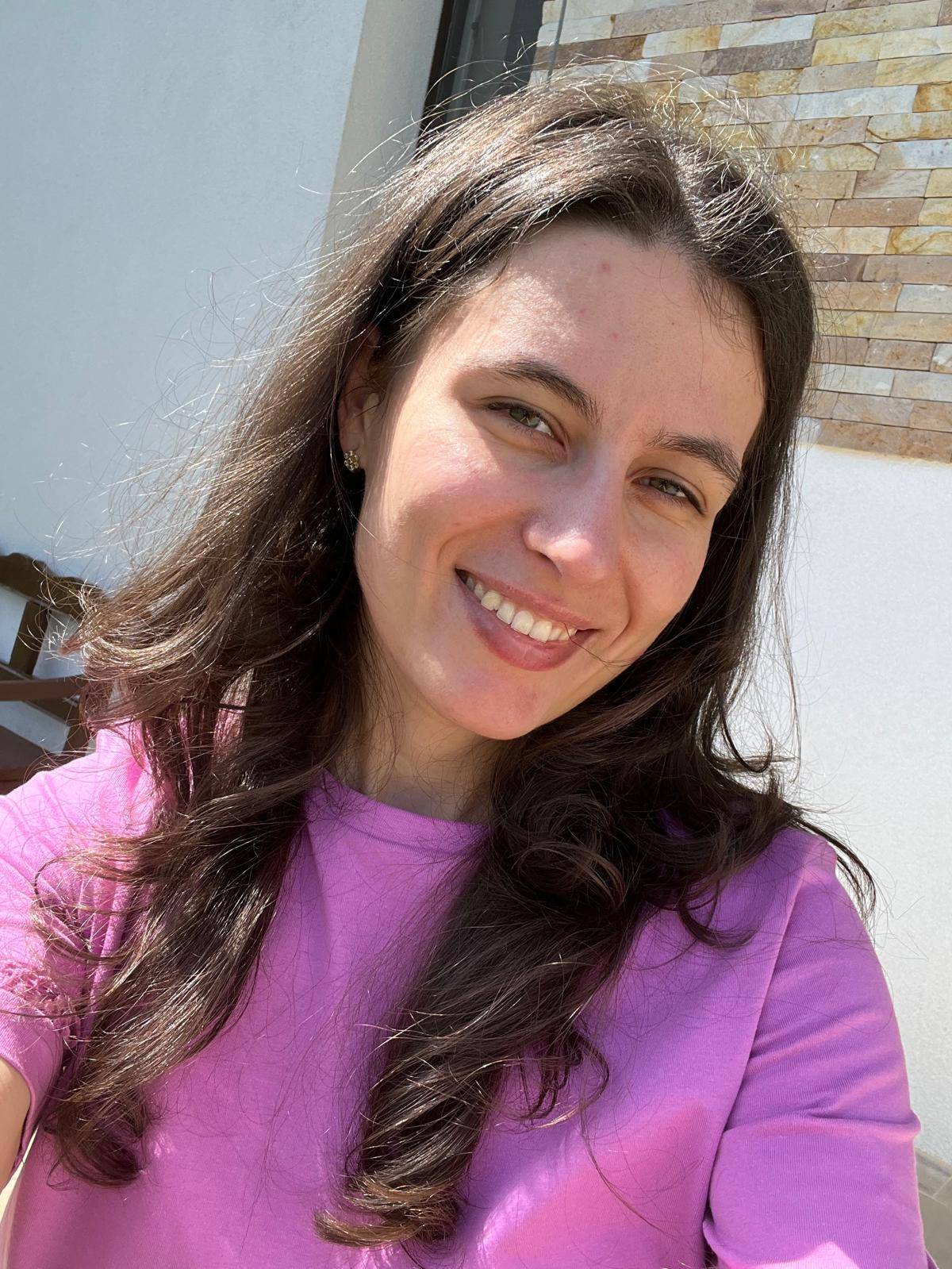 Profile selfie of Patricia smiling in the sun with a pink T-shirt