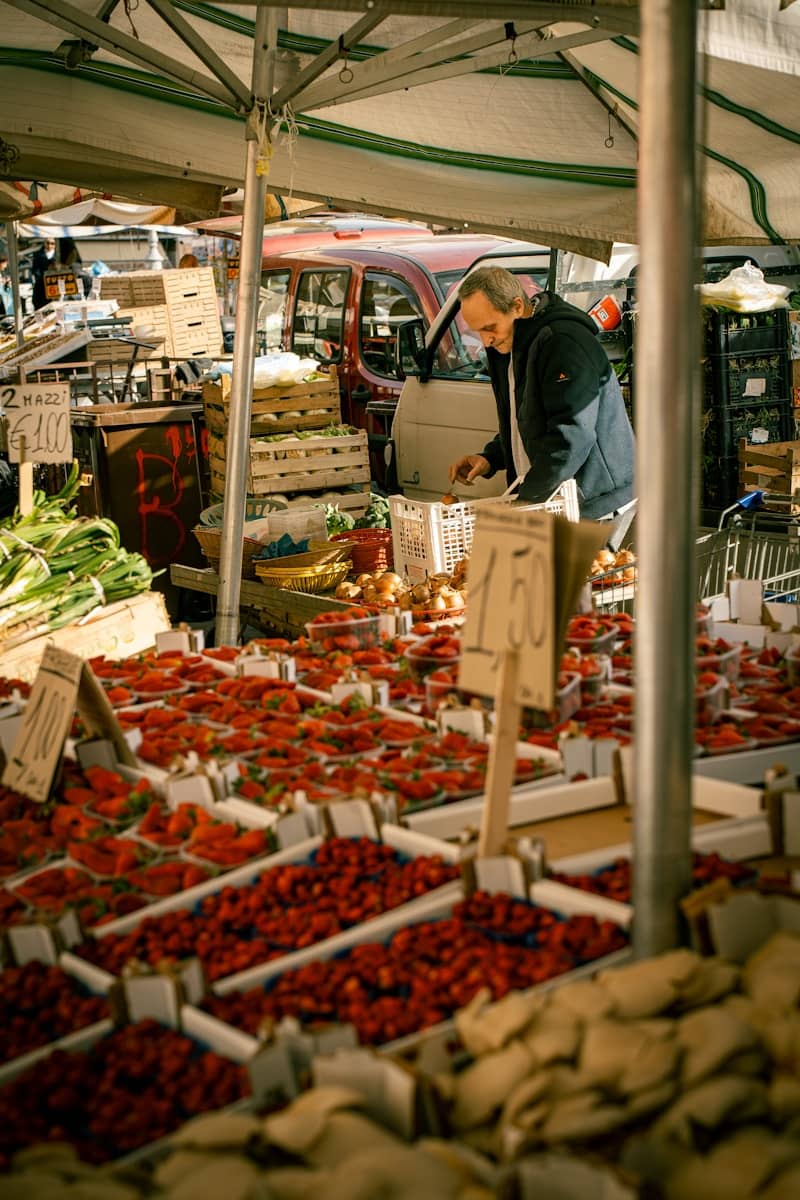 A man shops at a bustling outdoor produce market.