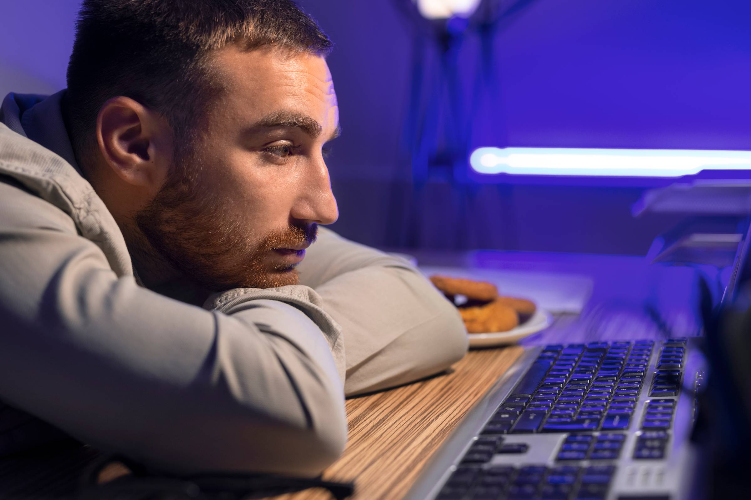 A man staring at his laptop in a dark room.