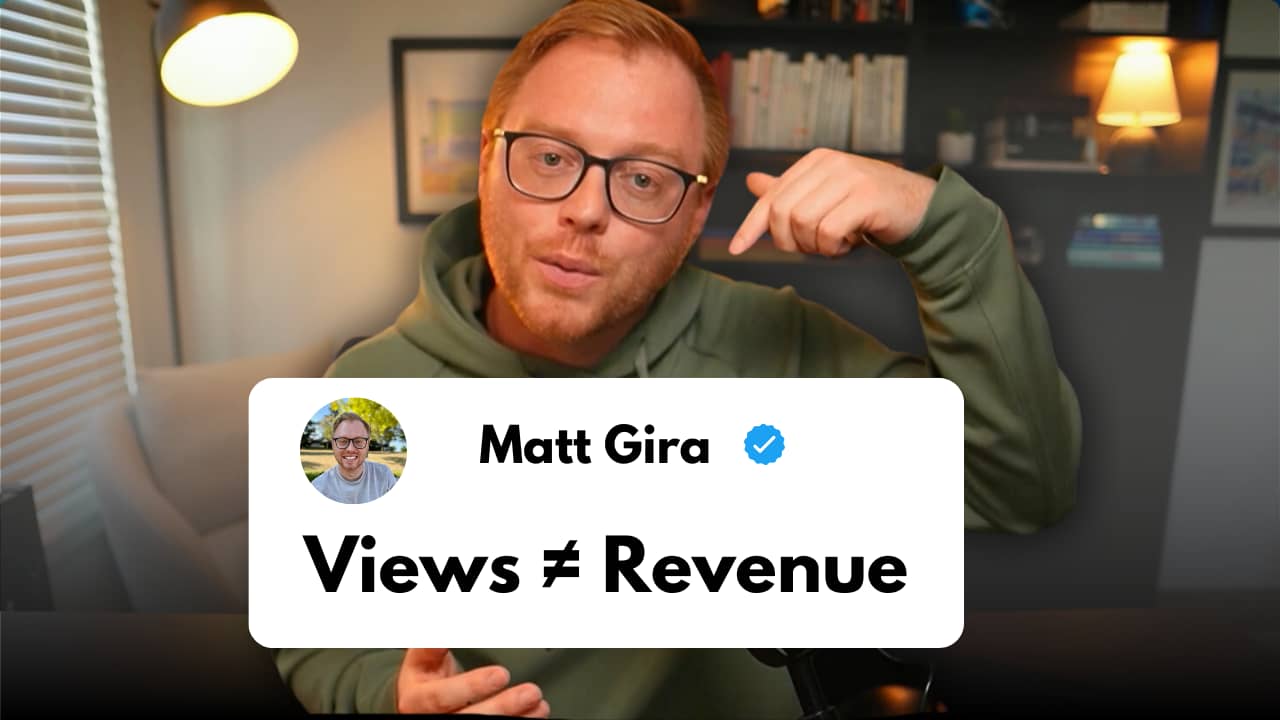 Matt Gira points to a caption reading ‘Views ? Revenue,’ emphasizing the difference between video views and actual revenue generation. He is wearing glasses and a green hoodie, sitting in a well-lit room with bookshelves and a desk lamp in the background.