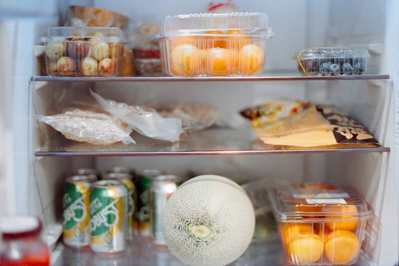 Various foods and drinks stocked inside an open refrigerator.