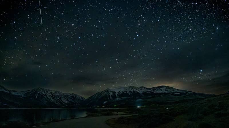Starry night sky over mountains and a lake