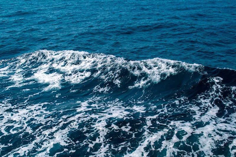 A blue ocean wave with white foam.