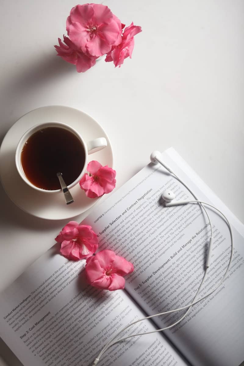 Tea, book, and flowers create a cozy study scene.