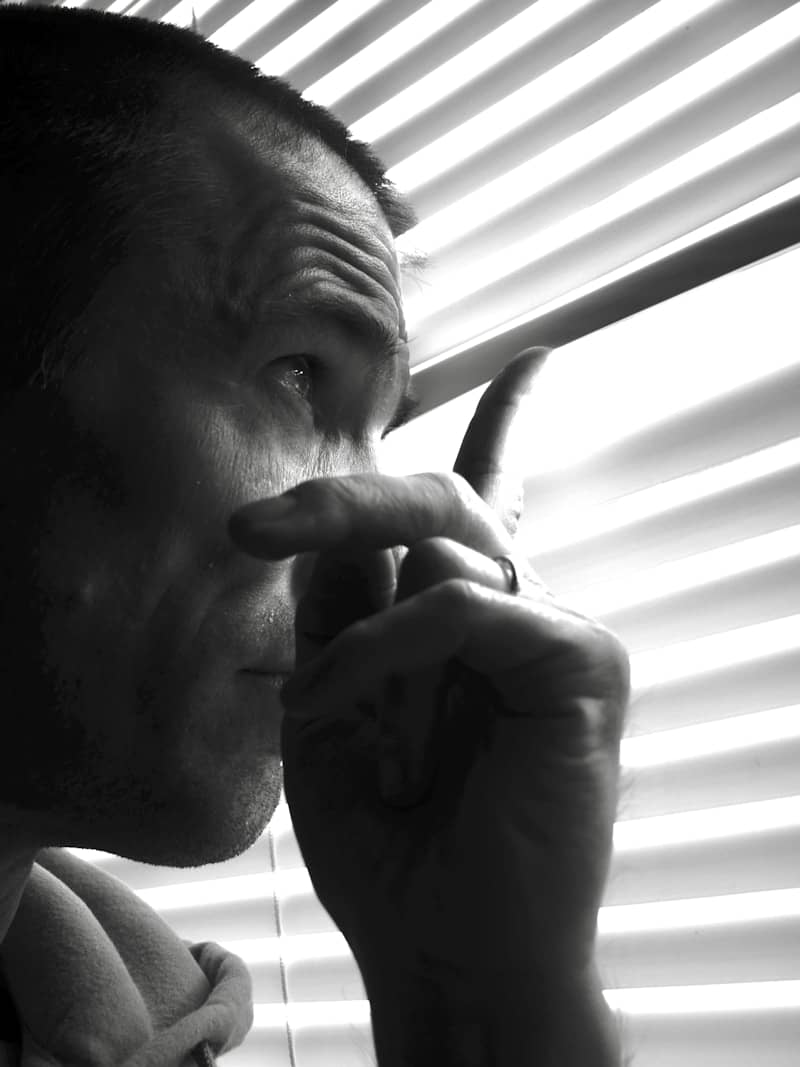 Man looking through window blinds