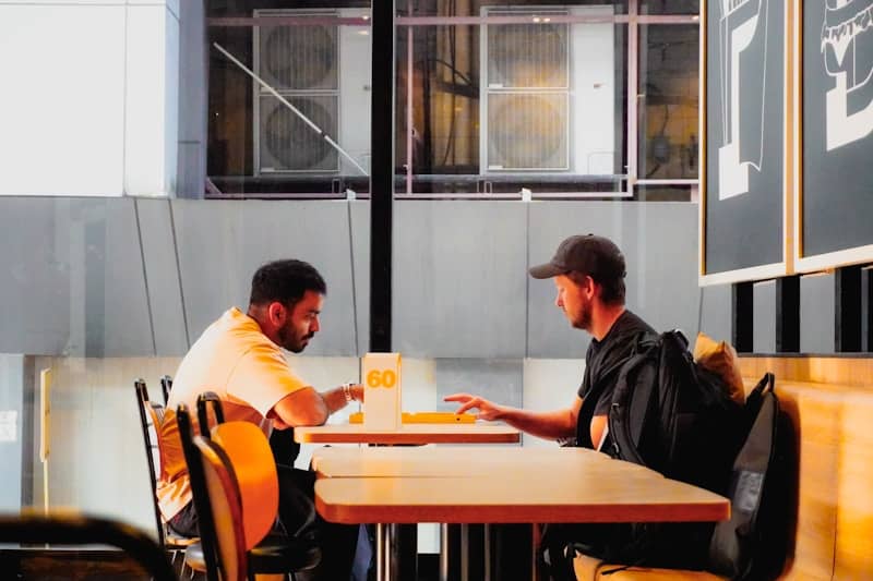 Two men sitting at a table talking.