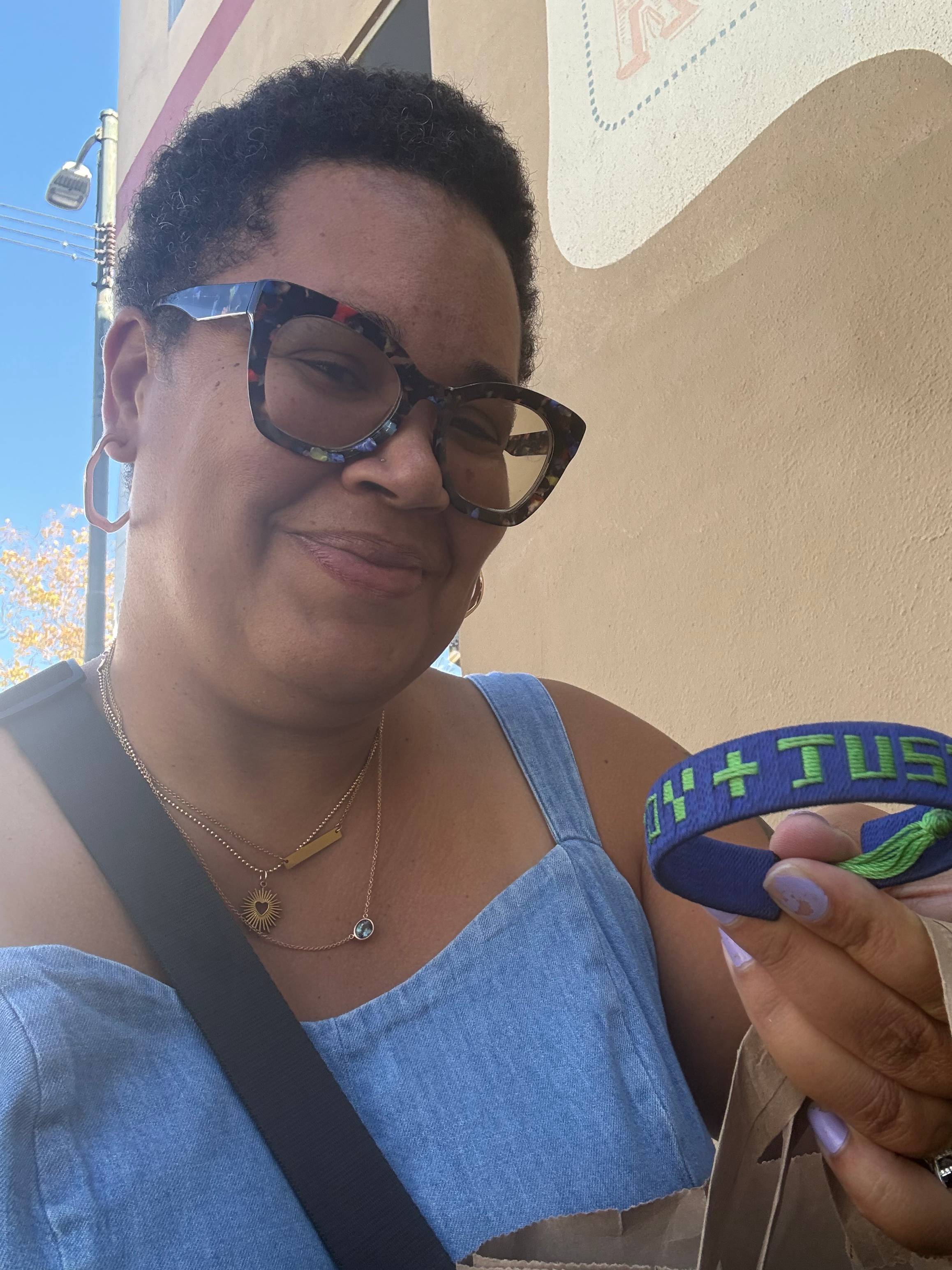 Mama J holds a blue bracelet that reads "Joy + Justice"