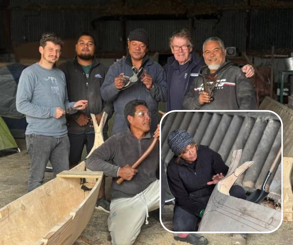 Six men are posing together in a workshop setting. Five are standing and one is kneeling in front, holding a hammer and chisel near a partially constructed wooden canoe. Several of the standing men are holding woodworking tools and smiling for the camera. The background includes tents, wooden planks, and various workshop materials. An inset image, in the lower right, shows a fair-skinned woman with a beanie, wearing a dark jacket, kneeling and looking intently at a wooden object that appears to be part of a larger structure, possibly a boat or a mold. She is holding a tool that resembles a small shovel or scoop.