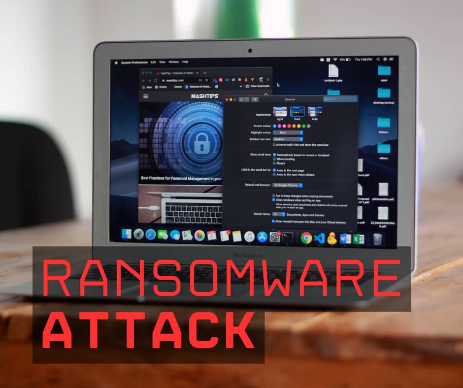MacBook laptop displaying cybersecurity content with a blue padlock icon on screen, overlaid with bold red text reading 'RANSOMWARE ATTACK' in large letters across the bottom of the image.