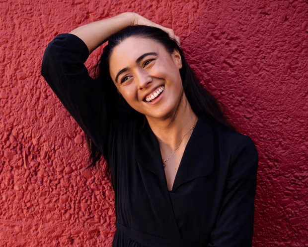 Portrait of Winnie Dunn, Tongan-Australian author from Western Sydney, smiling warmly against a neutral background, celebrating her shortlisting for the 2025 Miles Franklin Literary Award for her debut novel Dirt Poor Islanders.