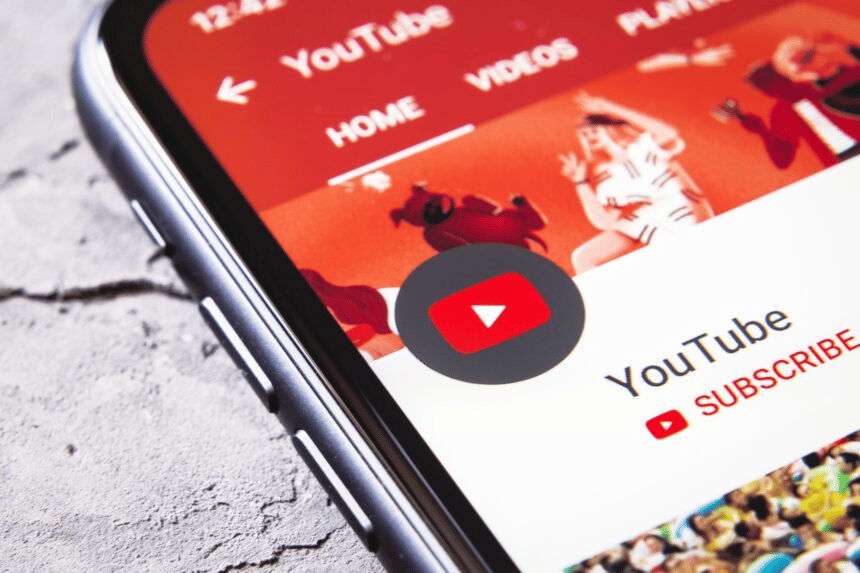 Close-up of an iPhone XR screen displaying the YouTube app icon prominently against a blurred background.