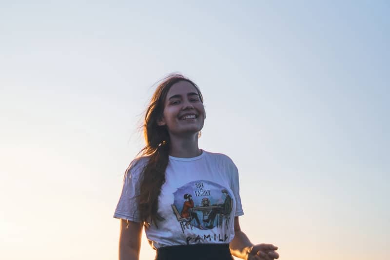 Happy woman smiling under a clear sky.