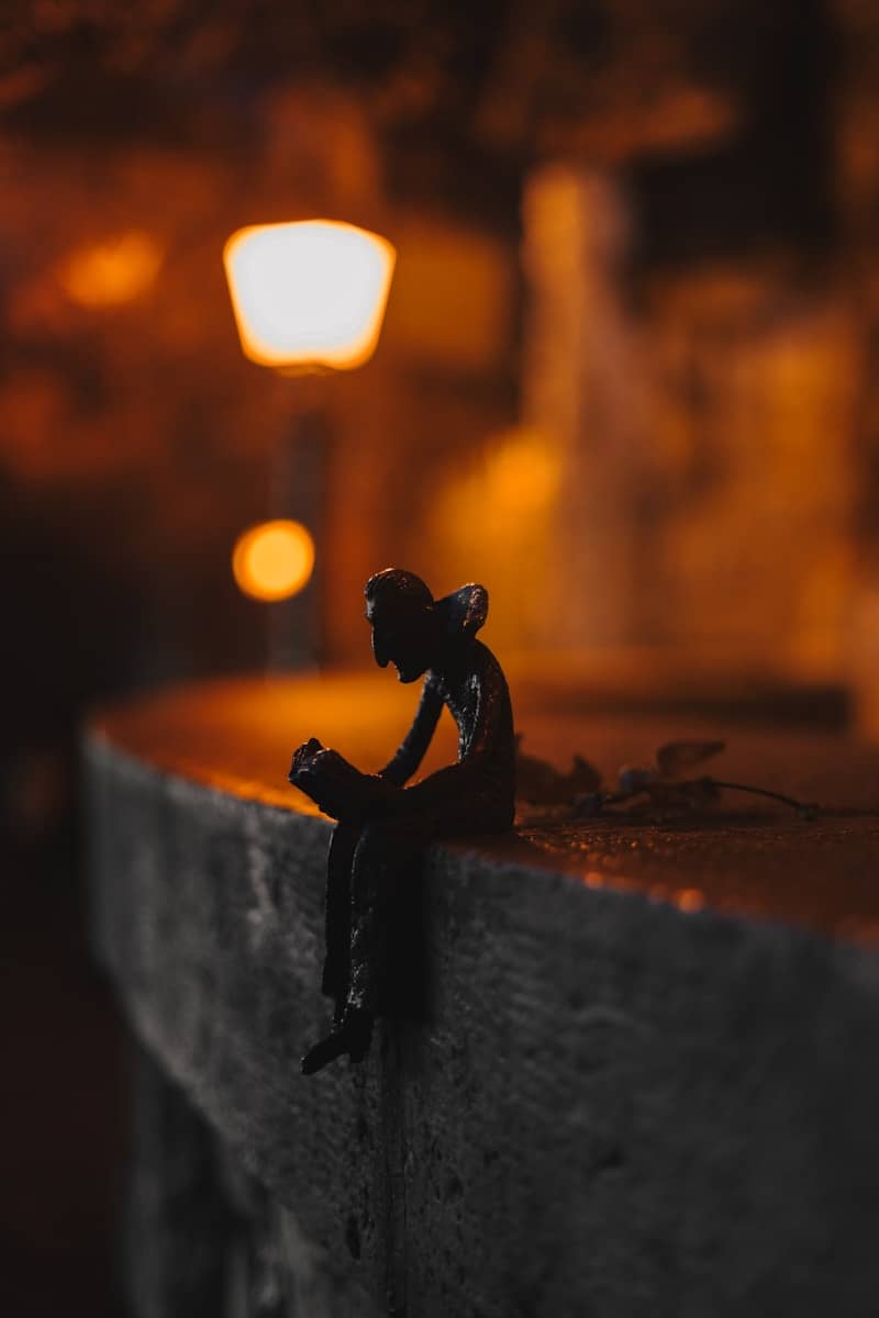 A small figurine sitting on a ledge next to a street light