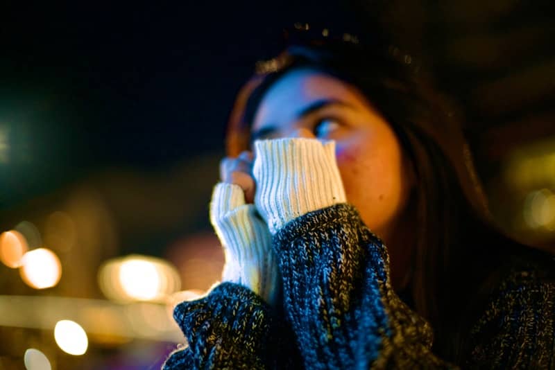 Woman holds her hands up while looking at something.