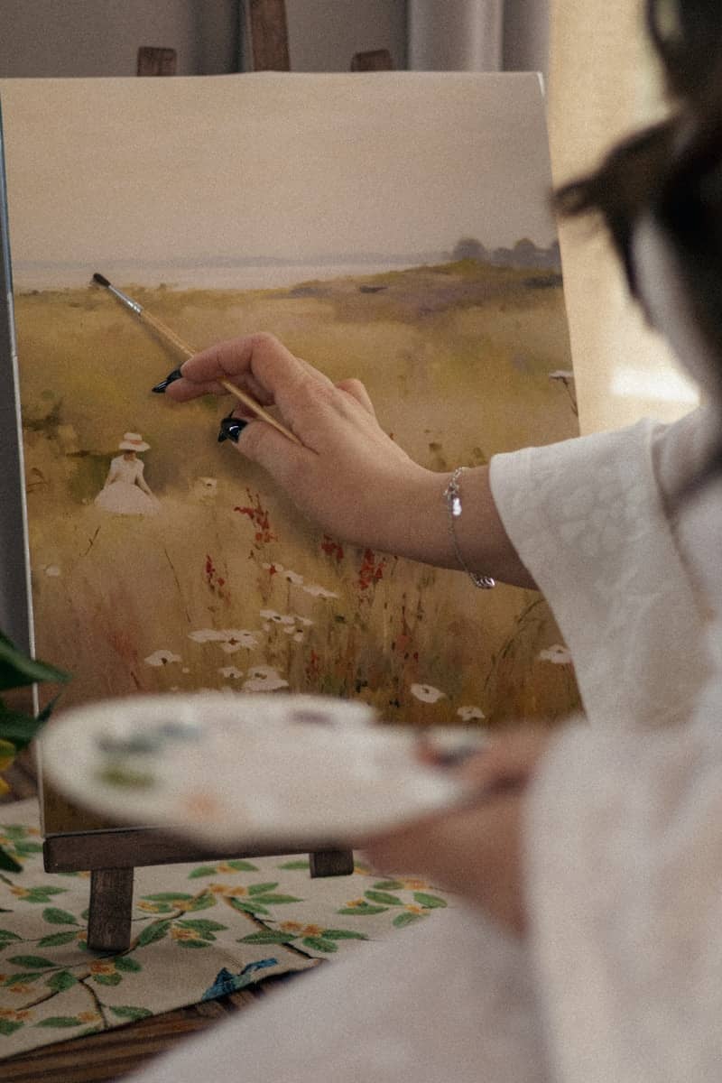 An artist paints a landscape on canvas.