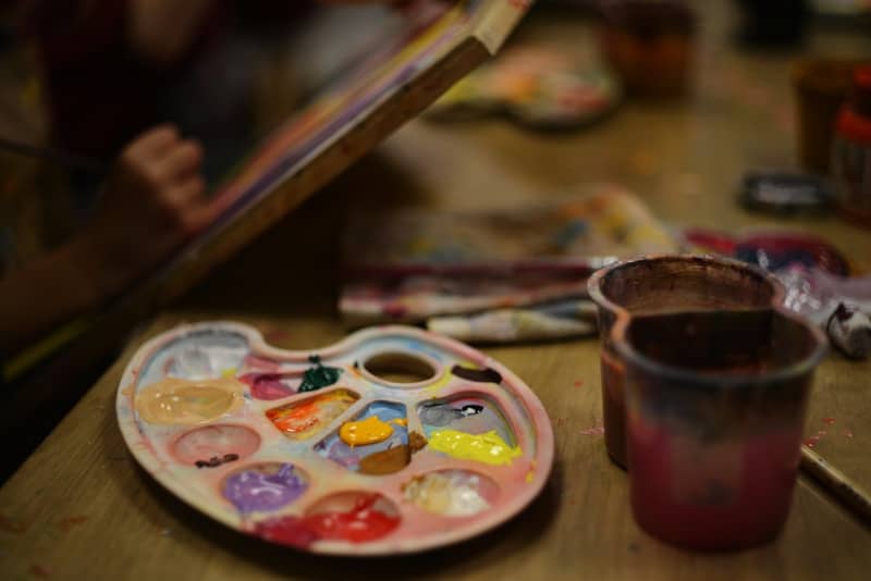 A plate with a paintbrush and a cup of paint