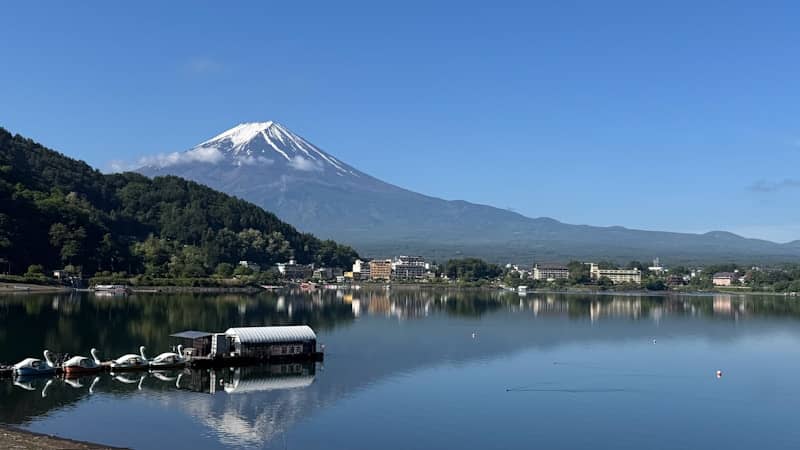 Mount fuji reflects in a calm lake with a town.