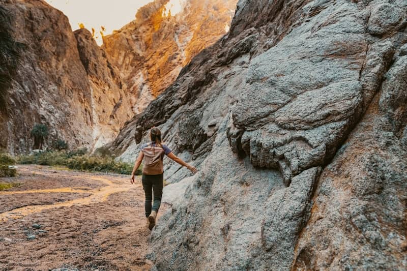 a woman climbing up a large rock in the mountains