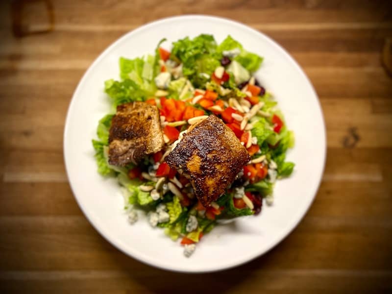 Grilled fish atop a fresh green salad