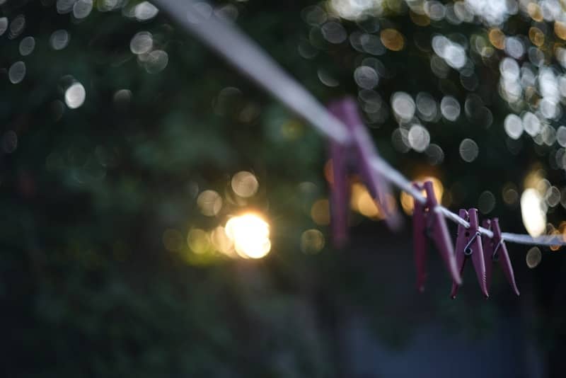 Clothespins hang on a clothesline with bokeh lights.