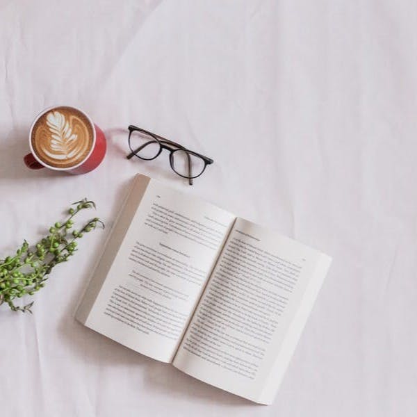 book page beside eyeglasses and coffee