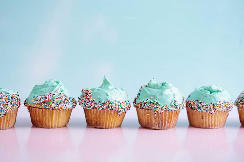 six teal icing cupcakes with sprinkles