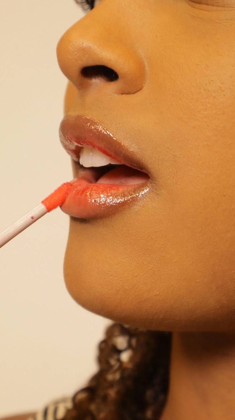 Applying lip gloss to lips.
