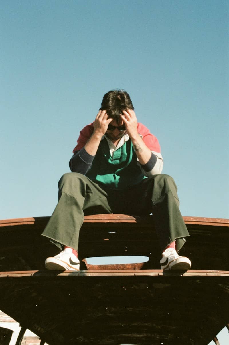 A person in a color-blocked rugby shirt and green trousers on a rusted metal roof