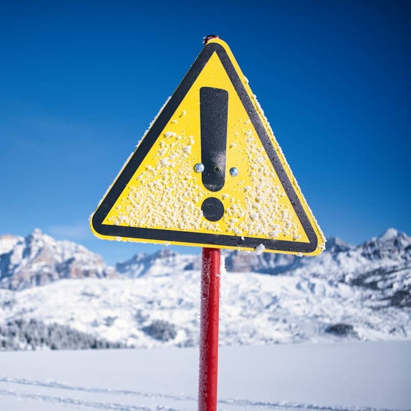 Yellow warning sign with exclamation mark in snow.