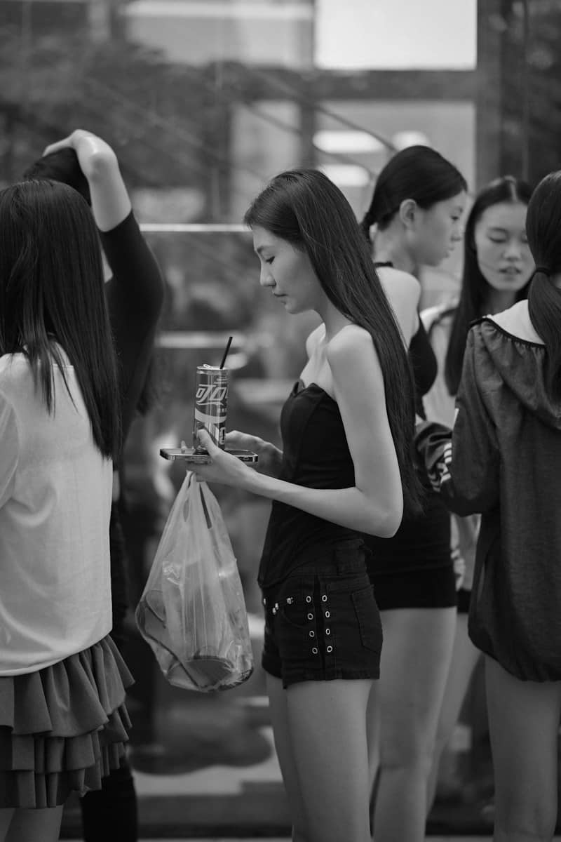 A woman holding a soda can and plastic bag among a group of people