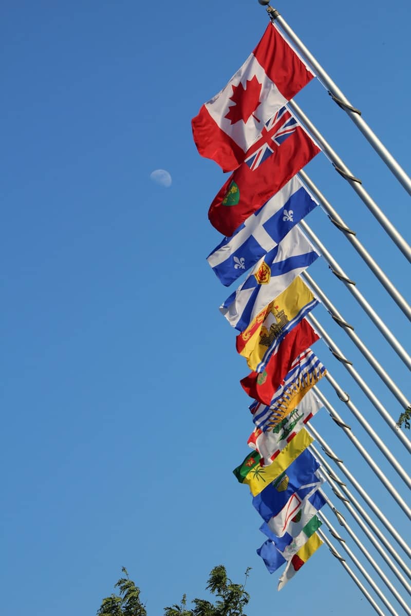 Canadian and provincial flags flying against a blue sky